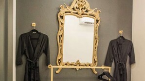 A bedroom with a dark wall, a large ornate mirror, and two black robes hanging on hooks. - "Speakeasy Suite" @ ArnoTriplex+Close to Dowtown+Pet Friendly! (Albuquerque)