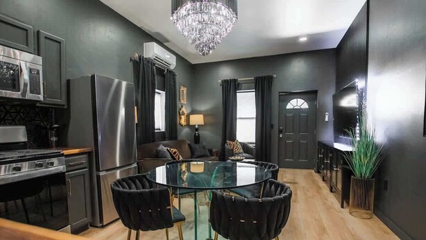 A modern kitchen with a glass dining table, black upholstered chairs, and a chandelier. - "Speakeasy Suite" @ ArnoTriplex+Close to Dowtown+Pet Friendly! (Albuquerque)