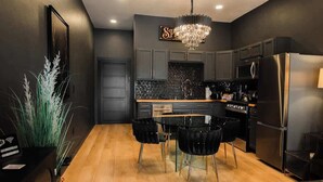 A modern kitchen with dark cabinetry, a black dining table, and a chandelier. - "Speakeasy Suite" @ ArnoTriplex+Close to Dowtown+Pet Friendly! (Albuquerque)