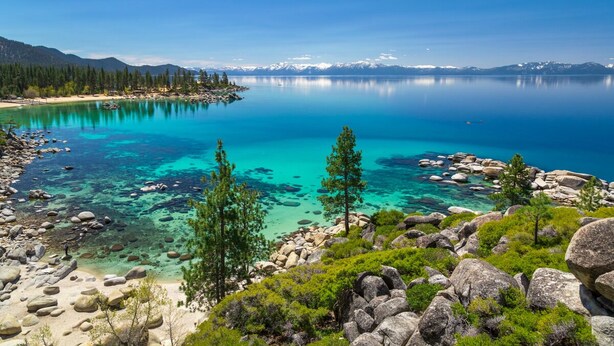 Une vue dégagée sur un lac entouré de montagnes et d’arbres.