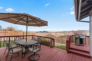 Enjoy outdoor dining and socializing in this patio area with a round table, comfortable seating, and a grill.