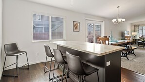 Une cuisine dotée d’un îlot central, de tabourets de bar et d’un coin repas avec des chaises et une table.