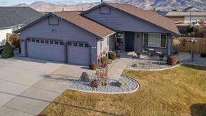 Une maison de plain-pied avec un garage, un patio couvert et une pelouse bien entretenue.