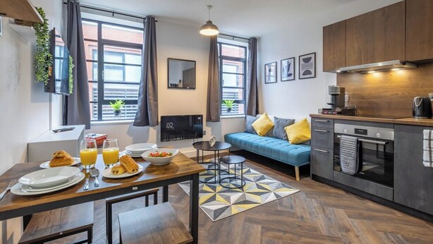 Un apartamento moderno con comedor, kitchenette y un sofá con cojines.