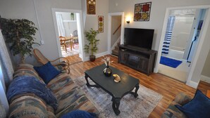 A living room with a sofa, a coffee table, a TV, and a staircase leading to another room. - Comfy Rustic Retreat 2 blocks from Mayo Hospital and Bethany College. (Mankato)