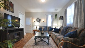 A living room with a sofa, a coffee table, a TV, and a plant. - Comfy Rustic Retreat 2 blocks from Mayo Hospital and Bethany College. (Mankato)