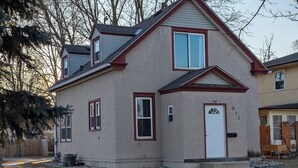 A two-story house with a gabled roof, a front door, and a small porch. - Comfy Rustic Retreat 2 blocks from Mayo Hospital and Bethany College. (Mankato)