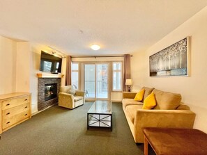 A living room with a fireplace, a sofa, a coffee table, and a television.