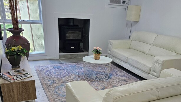 A modern living room with a white sofa, a round coffee table, a fireplace, and a large window. - Farm cottage in 2.3 acres. Fully renovated for your comfort.  (Newmerella)