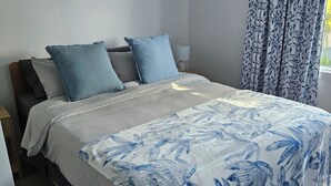A bedroom with a bed, pillows, a nightstand, a lamp, and a window with curtains. - Farm cottage in 2.3 acres. Fully renovated for your comfort.  (Newmerella)