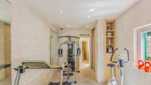 A gym with exercise equipment, a wall-mounted TV, and a window with kettlebells.