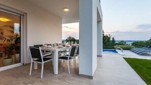 An outdoor dining area with a table set for four, a pool, and a view of the landscape.