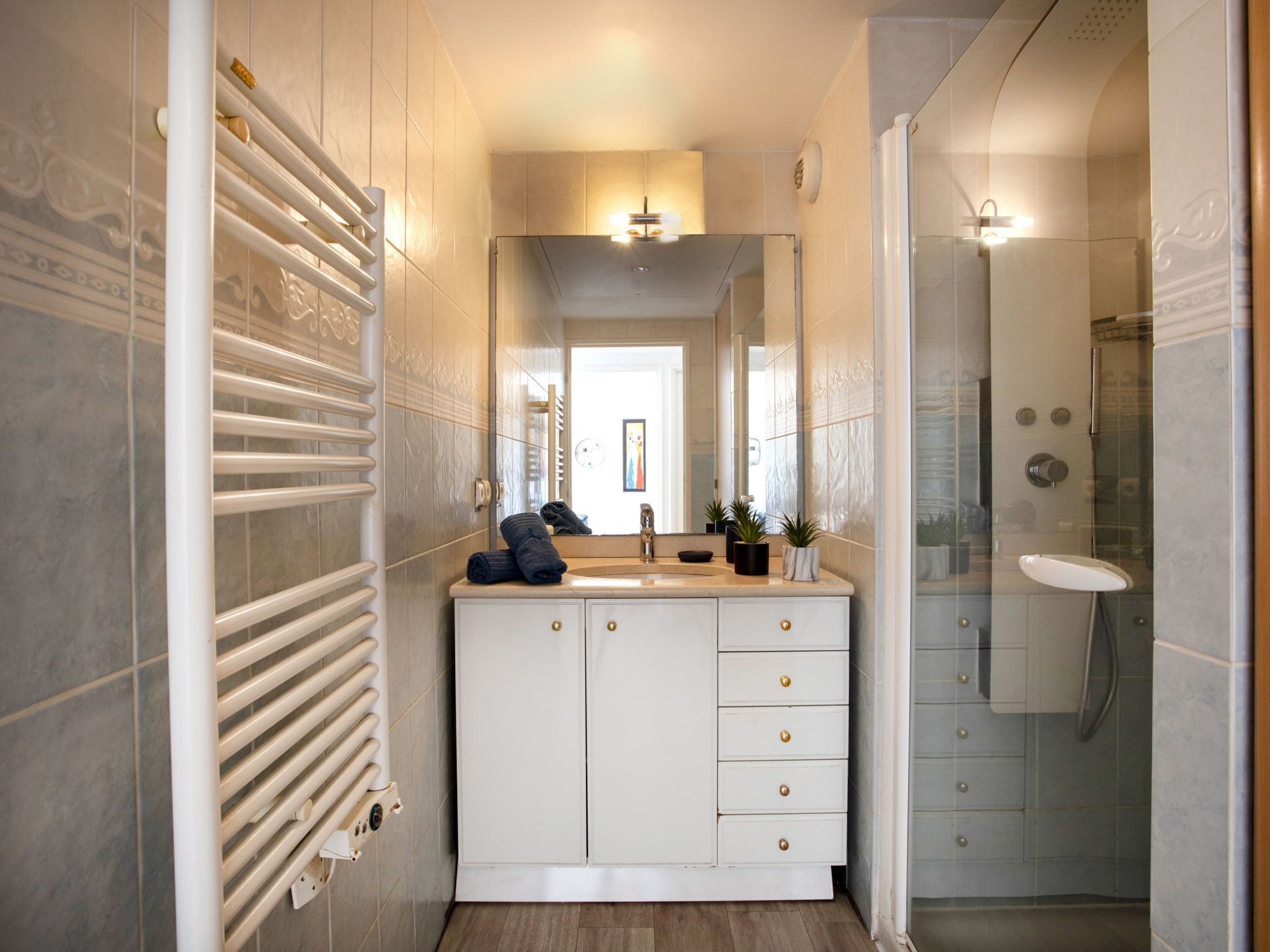 Une salle de bain moderne avec un meuble-lavabo blanc, une cabine de douche en verre et un radiateur.