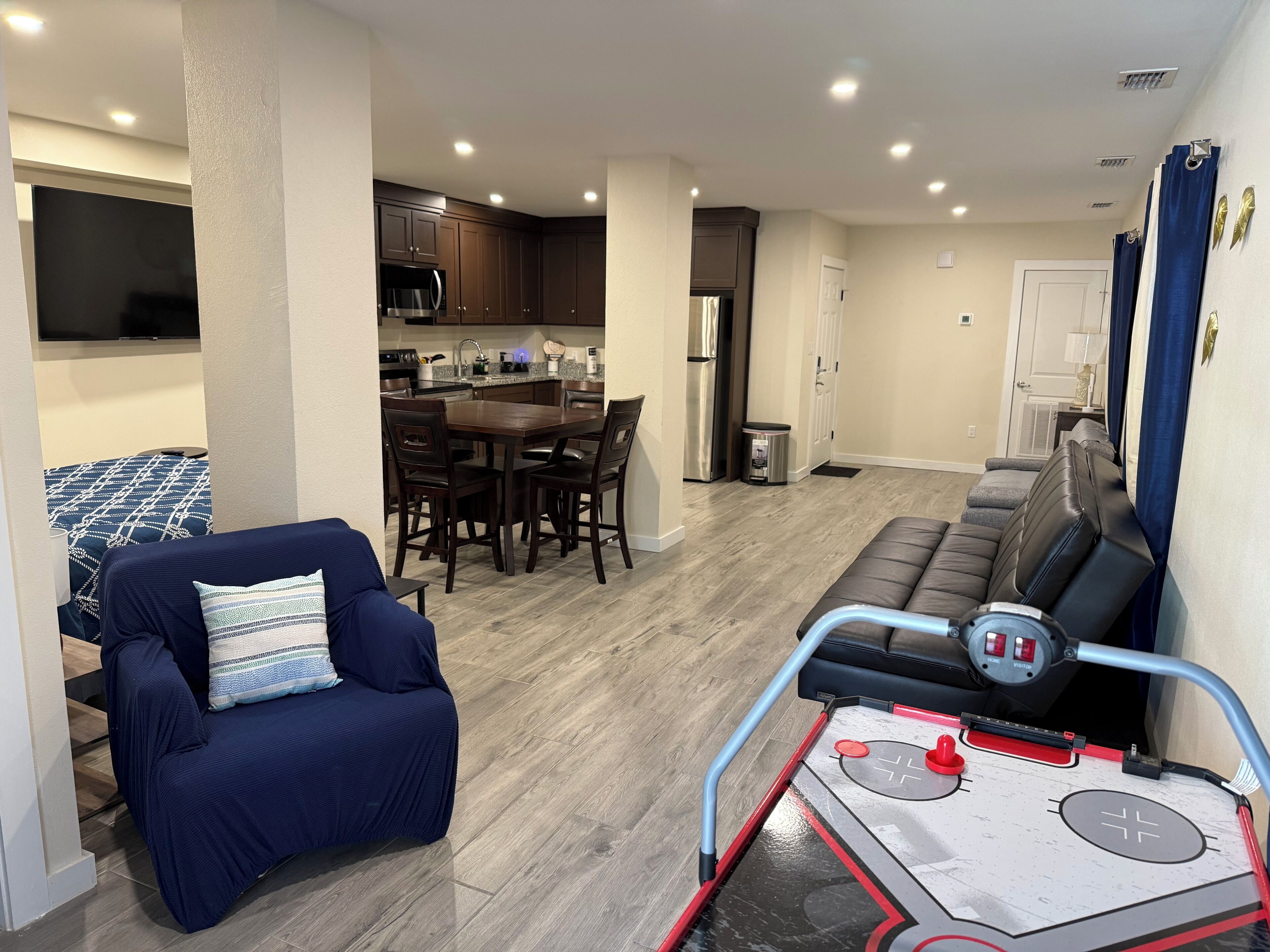 A modern living room with a sofa, a dining table, and a kitchen area with cabinets and appliances.