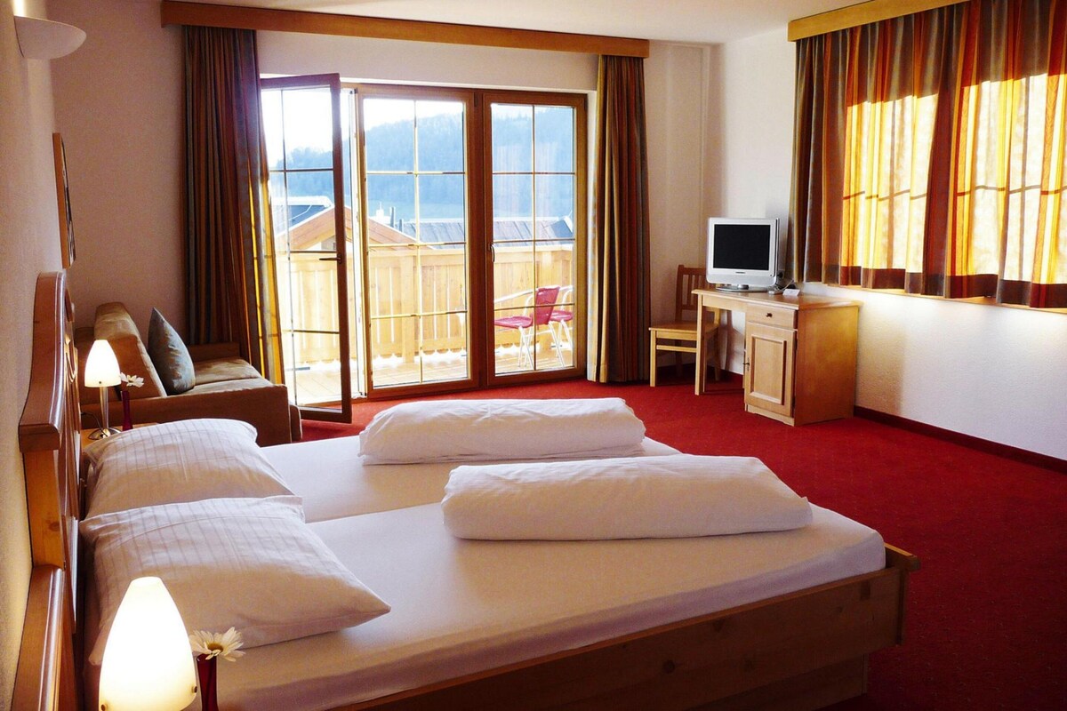 Une chambre d’hôtel avec un grand lit, un bureau, une télévision et un balcon avec vue.
