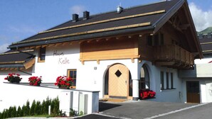 A building with a wooden balcony, a large arched entrance, and red flowers in front. - Holiday Home, Fiss (Fiss)