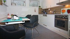 A modern kitchen with a dining table, chairs, and a built-in oven.
