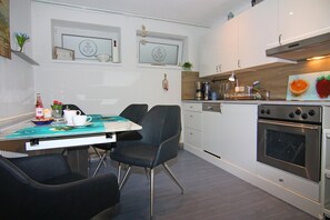 A modern kitchen with a dining table, chairs, and a built-in oven.