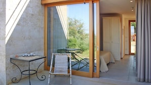Un balcon avec une porte-fenêtre, une table avec une chaise et un lit à baldaquin.