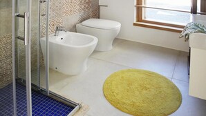 Une salle de bain avec une douche, un bidet, des toilettes et un tapis jaune sur le sol.
