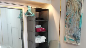 Una habitación compacta con escritorio, perchero, estante y un cuadro.