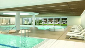 Una piscina interna moderna con diverse corsie, poltrone relax e un’area solarium.