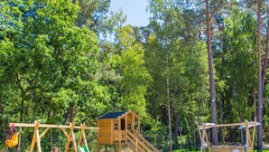 A wooden play structure with a slide, swings, and a small house. - Comfortable Holiday Cottages, Pobierowo (Rewal)