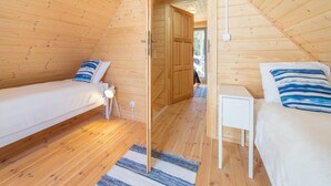 A cozy attic bedroom with two beds, wooden walls, and a small bedside table. - Comfortable Holiday Cottages, Pobierowo (Rewal)