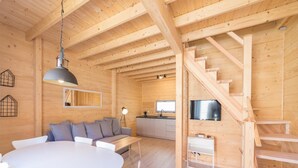 A wooden interior with a dining area, sofa, TV, staircase, and kitchen. - Comfortable Holiday Cottages, Pobierowo (Rewal)