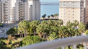 A high-rise residential building with multiple balconies, a parking area, and a view of the sea. - Apartment 'Mistral Apartment La Manga' with Sea View, Wi-Fi and Air Conditioning (San Javier)