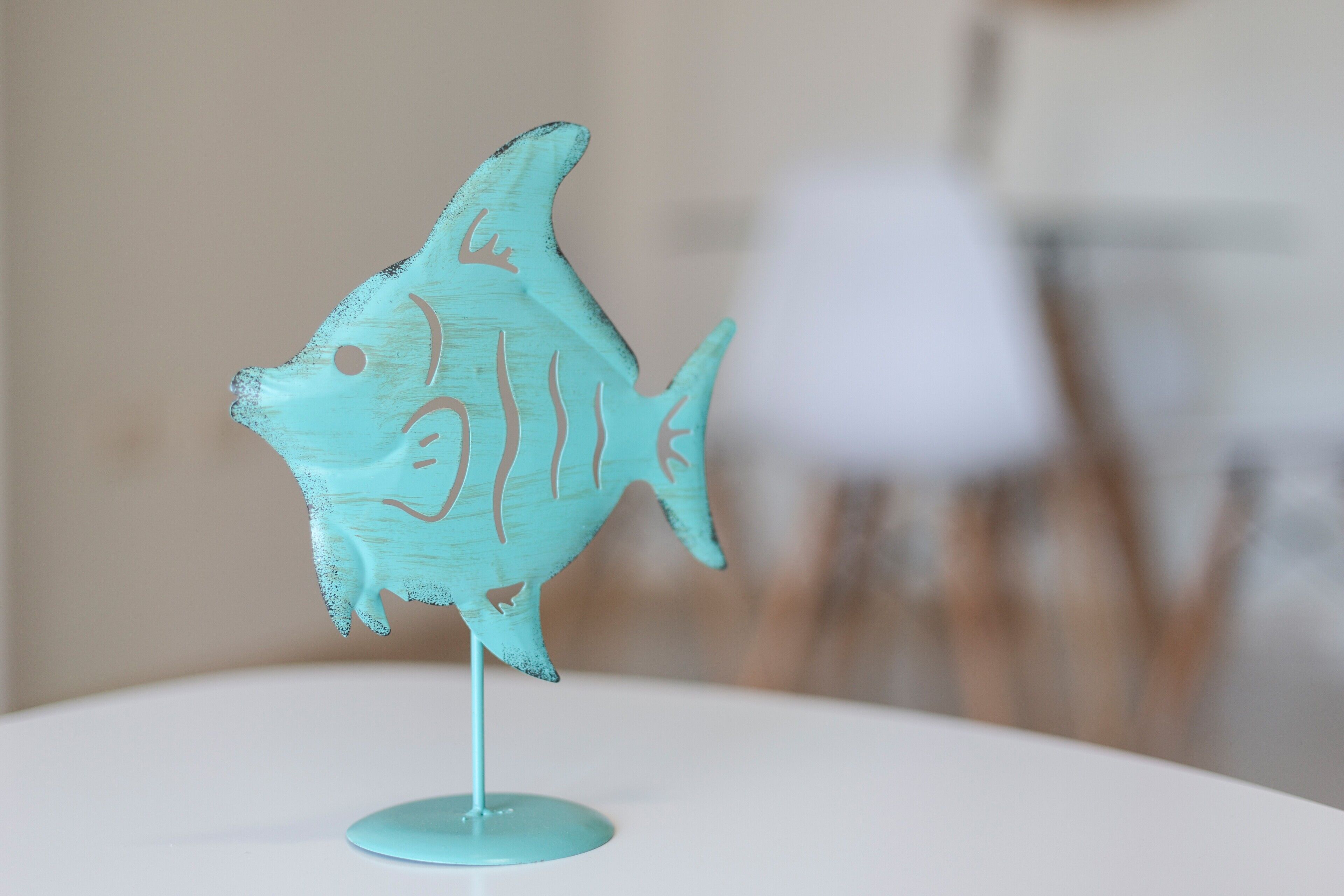 Un objet de couleur turquoise en forme de poisson, posé sur une surface blanche.