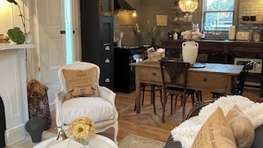 A cozy living room with a fireplace, a dining area, and a kitchen with a large window. - The Chateau On Pascal (Rockport)