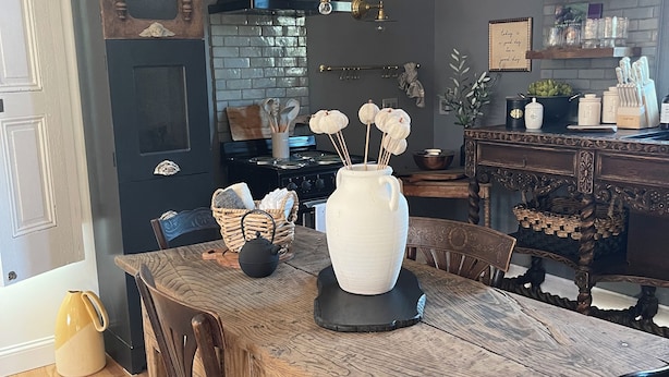 A dining area with a wooden table, chairs, a chandelier, and a kitchen in the background. - The Chateau On Pascal (Rockport)