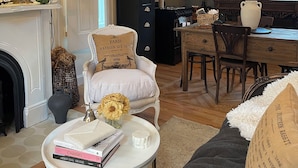 A cozy living room with a fireplace, a dining area with a chandelier, and a kitchen with a large window. - The Chateau On Pascal (Rockport)