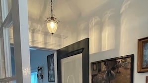 A hallway with a black door, a chandelier, and framed artwork on the walls. - The Chateau On Pascal (Rockport)
