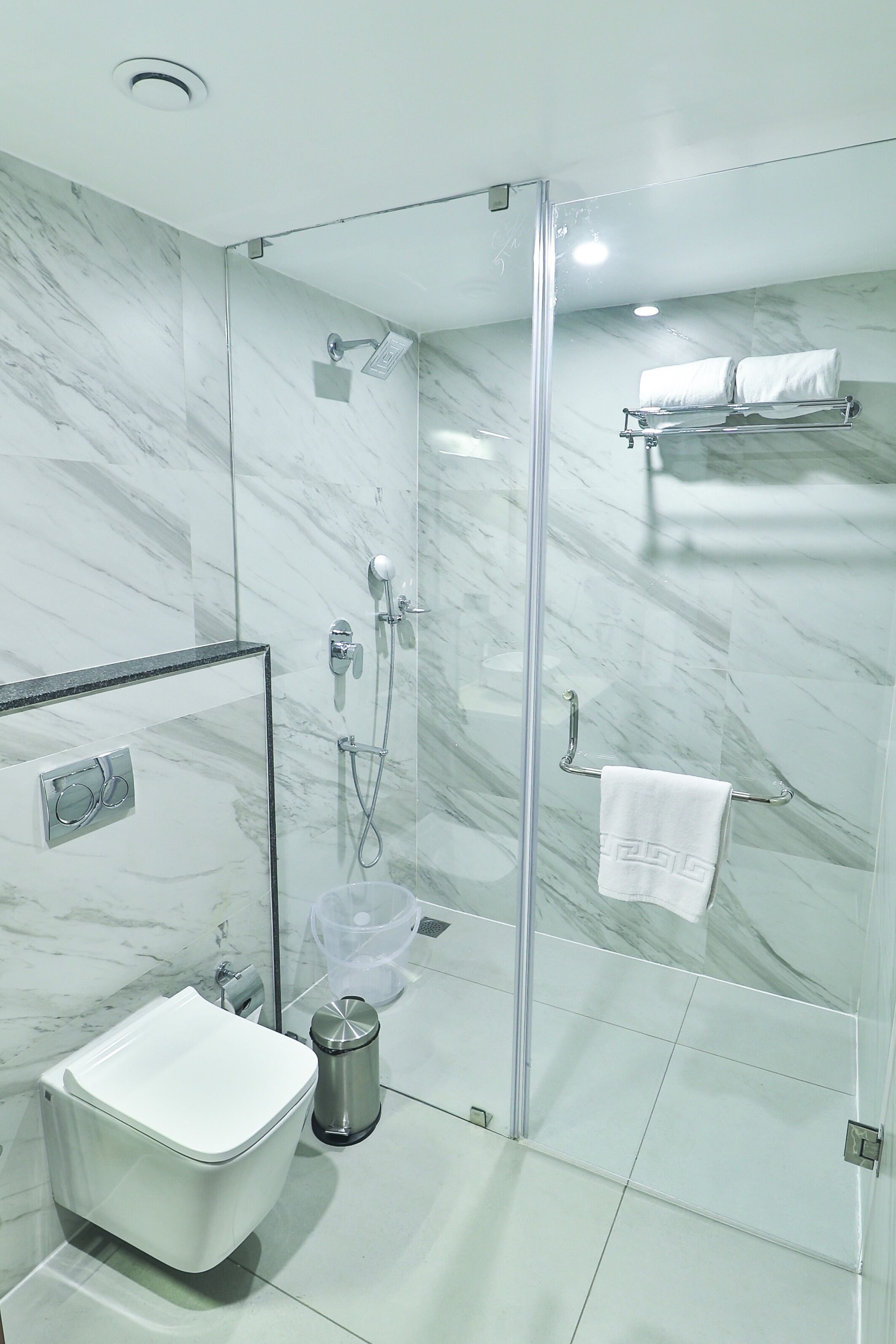 A modern bathroom with a glass-enclosed shower, a white sink, and a towel rack.