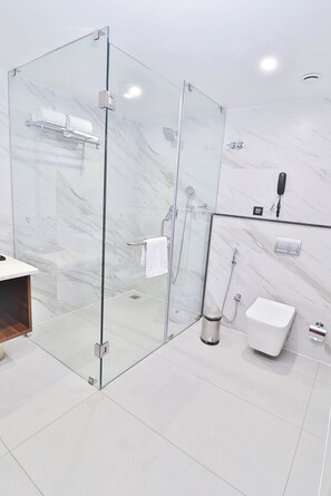 A modern bathroom with a glass-enclosed shower, a white toilet, and a marble-tiled wall.