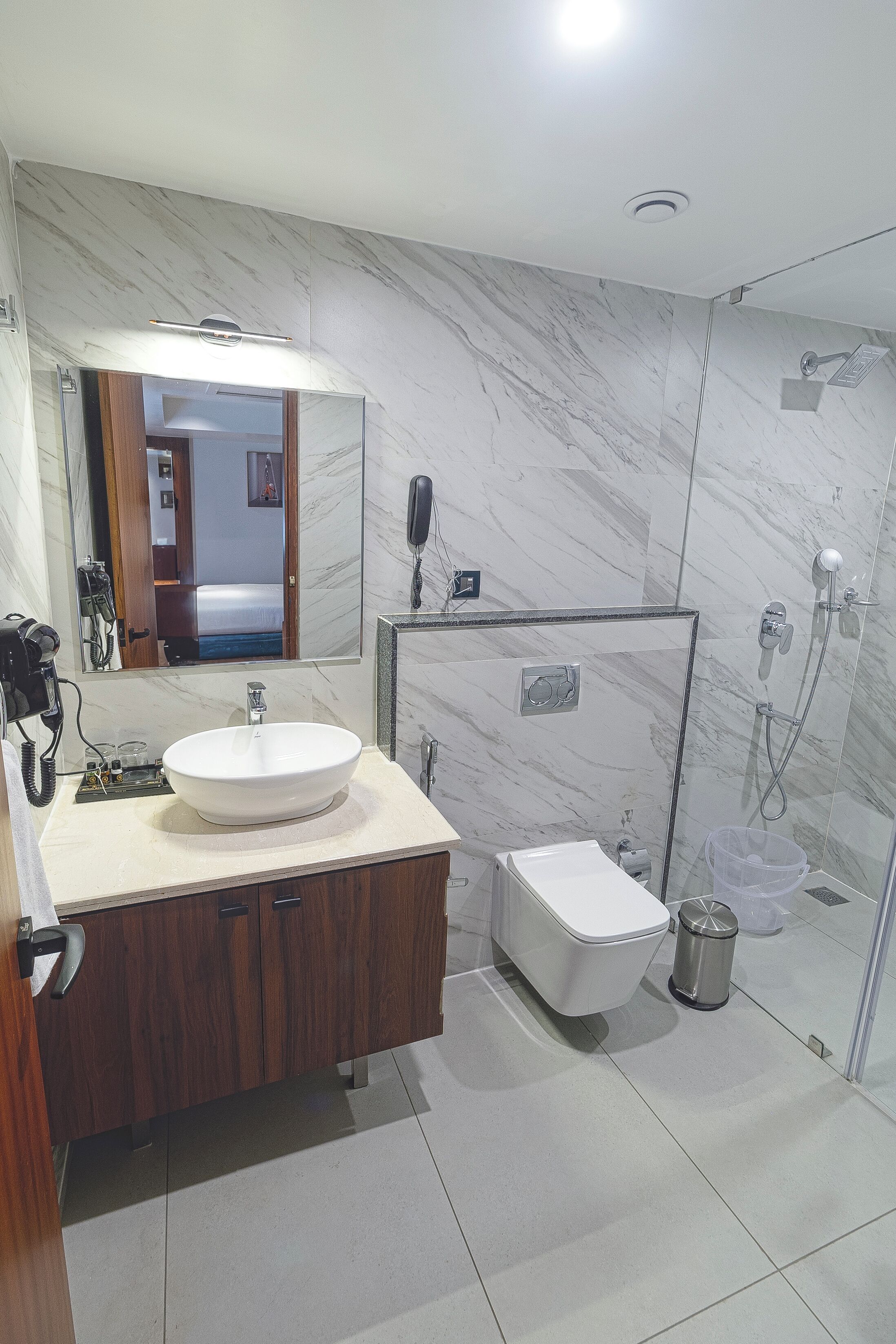 A modern bathroom with a marble sink, a glass-enclosed shower, and a toilet.