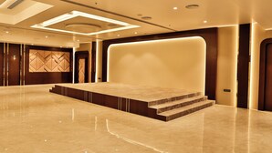 A spacious lobby with a polished marble floor, a central stage, and a modern ceiling design. - Royal Ritis  (Belagavi)