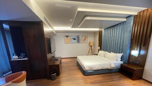 A modern hotel room with a large bed, a desk, a chair, and a bedside table. - Royal Ritis  (Belagavi)