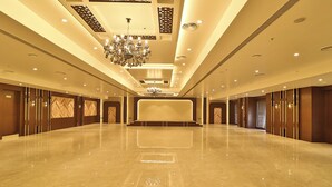 A spacious, well-lit hotel lobby with a polished marble floor, a grand chandelier, and a large, neutral-colored wall at the end of the corridor. - Royal Ritis  (Belagavi)