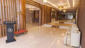 A luxurious lobby with a red carpet, a gold reception desk, and a row of white armchairs.