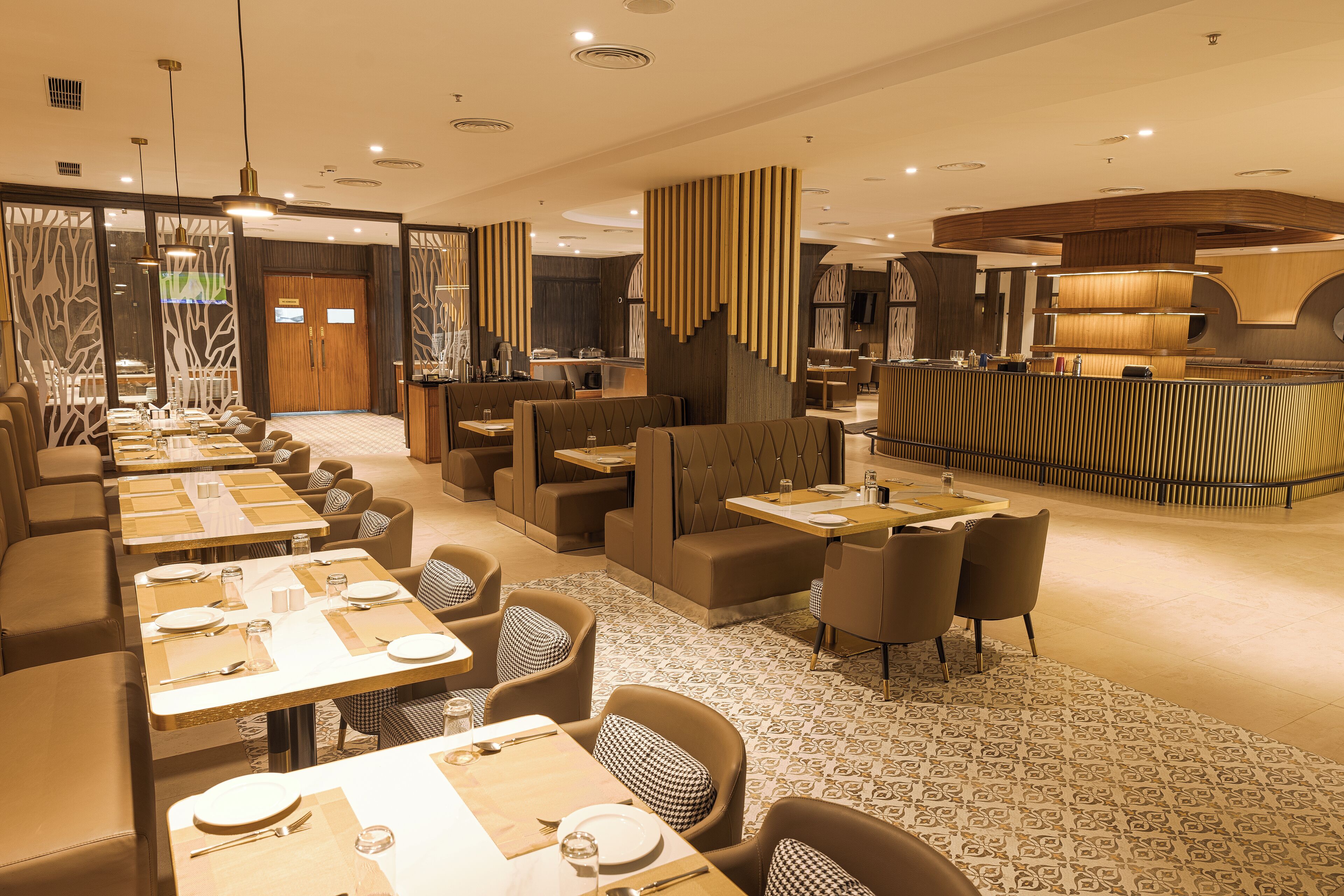 Un restaurante moderno con varias zonas de comedor, incluyendo reservados y mesas, y una barra central.