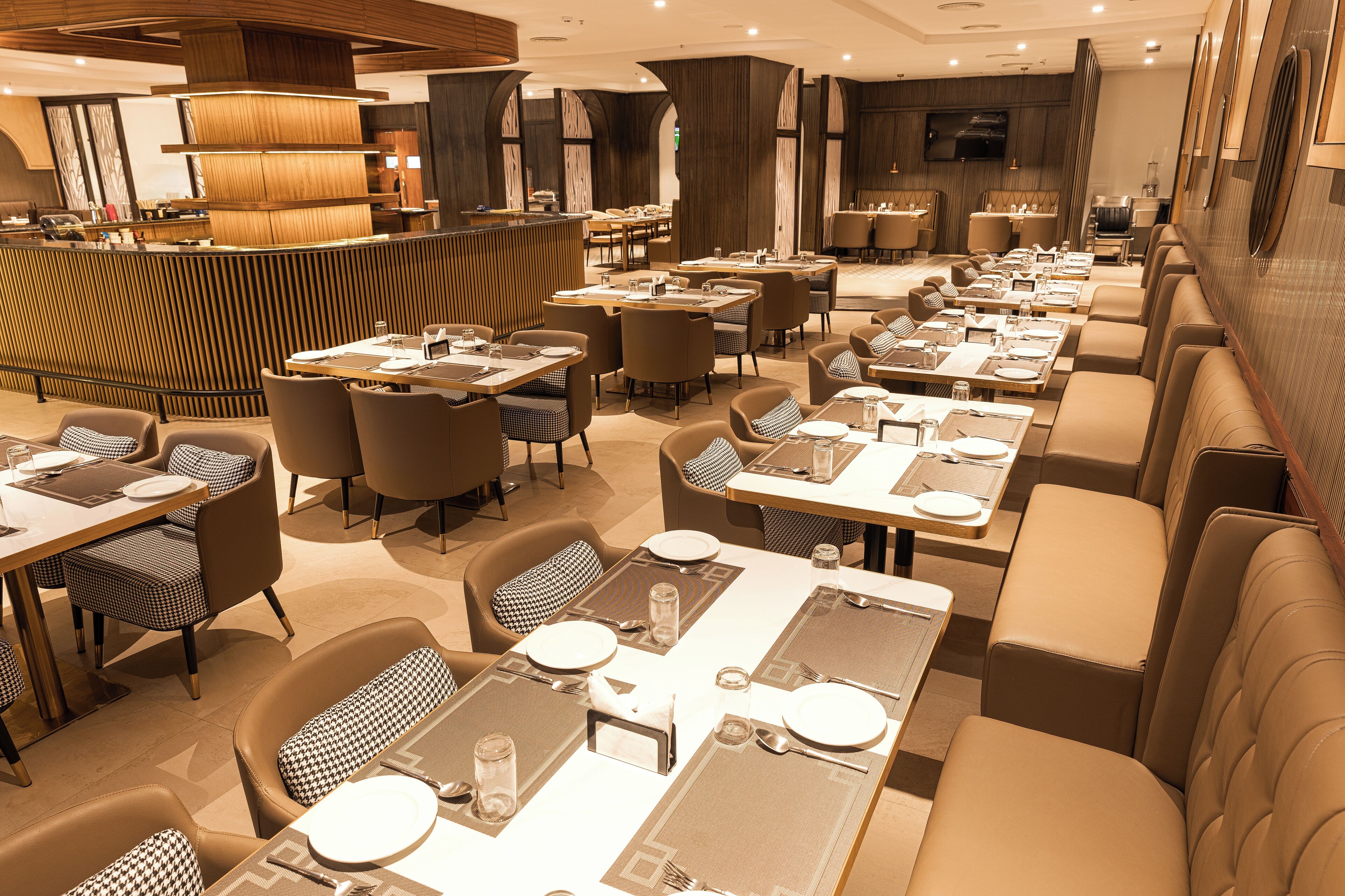 A restaurant with multiple dining tables and booths, a counter, and a television screen on the wall.