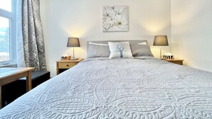A neatly arranged bedroom with a large bed, two bedside tables, a window with curtains, and a wall-mounted artwork. - Canmore Windtower Hotel Room  (Canmore)
