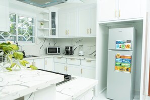 A modern kitchen with white cabinets, a refrigerator, a microwave, and a coffee maker. - Apartament Luxury at Bonao (Bonao)