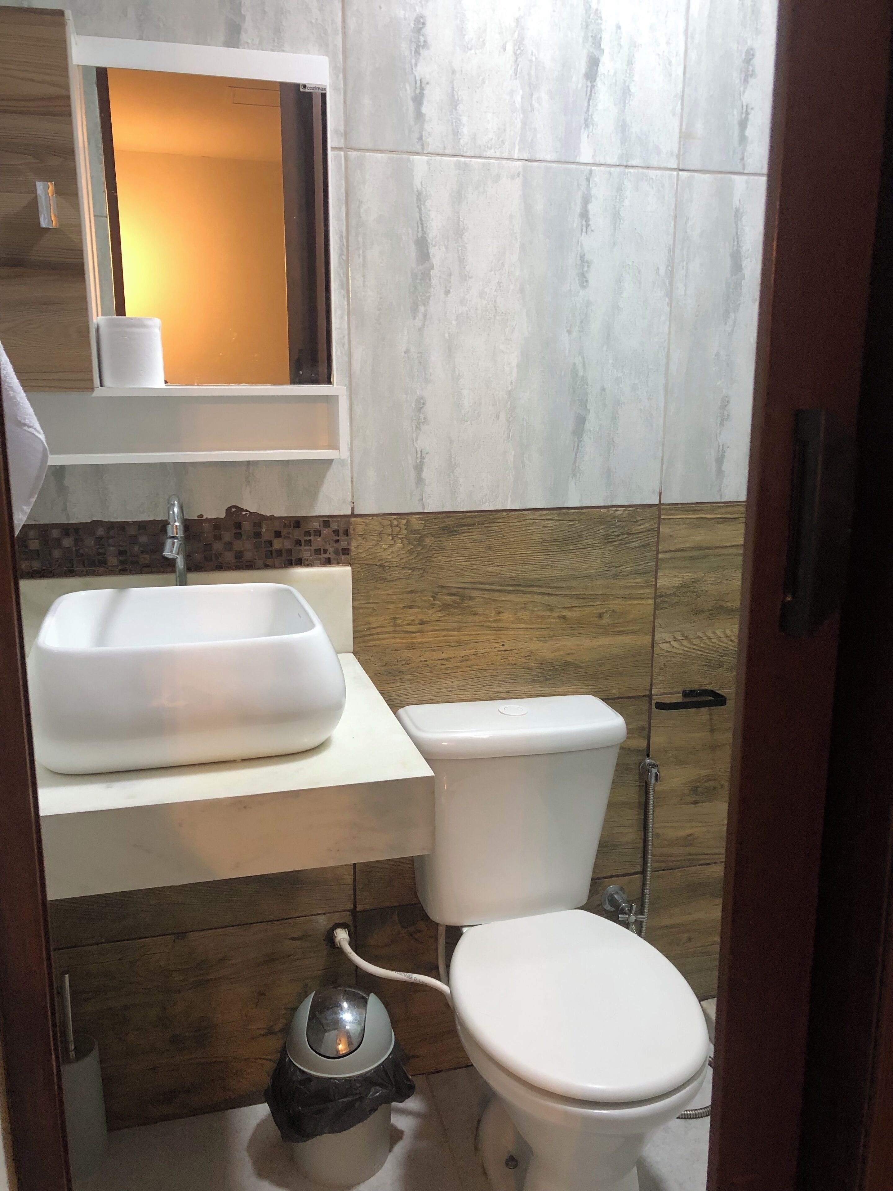 Un baño con un lavamanos blanco, inodoro y un cubo de basura.