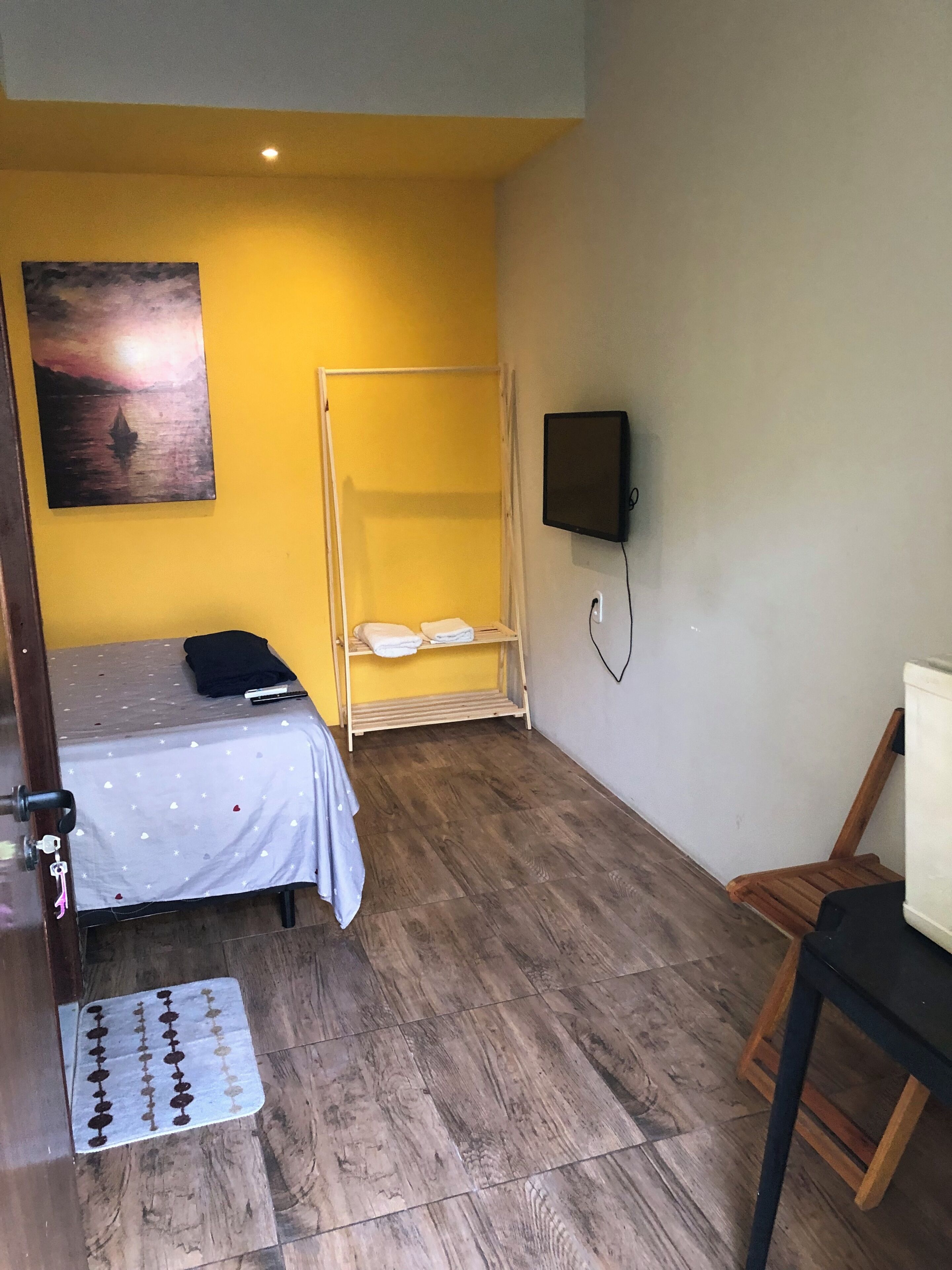Una habitación con una cama, un banco, un televisor y un cuadro en la pared.