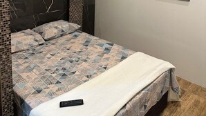 A bedroom with a bed, a painting of a sunset, and an air conditioning unit. - Pousada Galeria  (Vera Cruz)