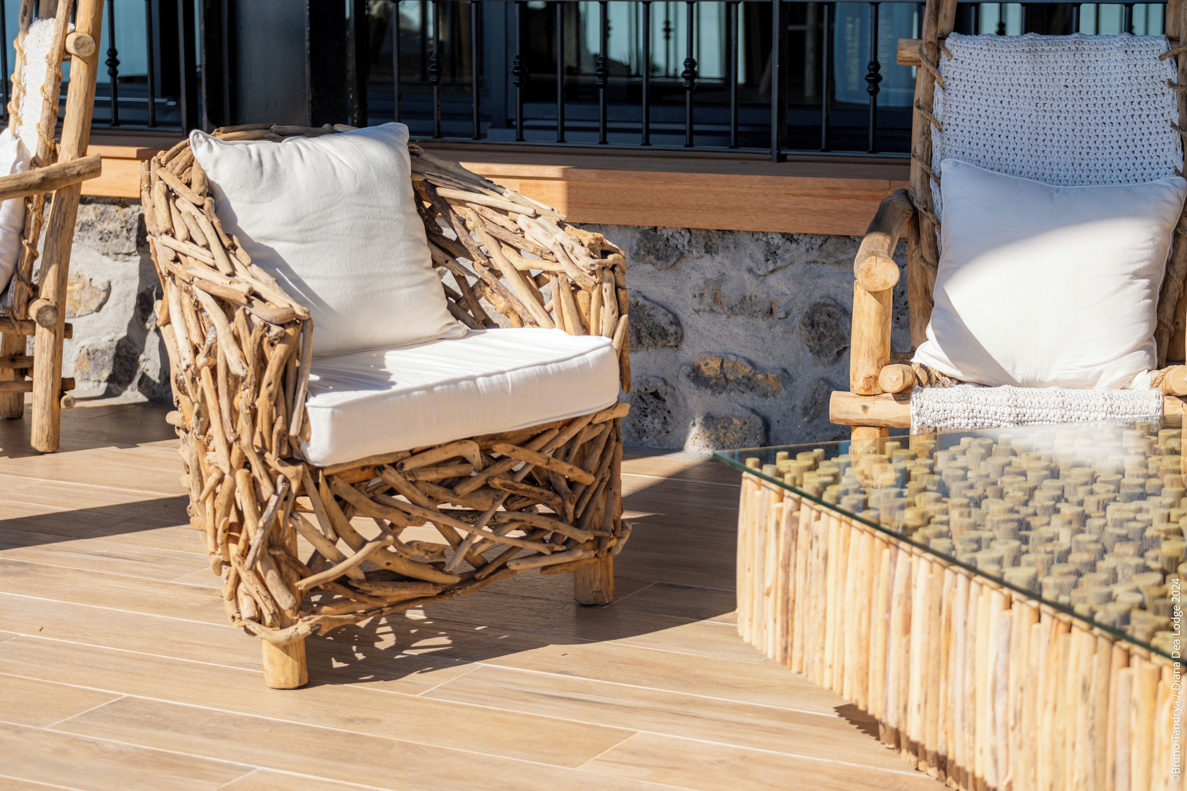Wicker lounge chairs with white cushions on a wooden deck.